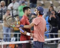 Novak Djokovic of Serbia (L) meets Lorenzo Musetti of Italy at the net after defeating him in a men