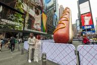 The artists Jen Catron and Paul Outlaw pose in front of âHot Dog in the Cityâ, in Times Square in New York on Tuesday, April 30, 2024. The 65 foot long animatronic hot dog sculpture raises up and ejaculates confetti at noon each day. The installation will be on display until June 13.(Â Richard B. Levine
