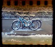 A snow encrusted bicycle chained to a bike rack in the Chelsea neighborhood of New York, March 2024. Photographed on film with an instamatic camera. ( Richard B. Levine