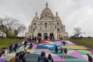 Vincent Isore\/IP3 ; Paris, France April 19, 2024 - People walk up the stairs leading to the Sacre Coeur basilica decorated with a fresco in Olympic colors as part of the preparations for the Paris 2024 Olympic Games. Less than 100 days remain for