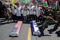 April 5, 2024 - Tehran, Iran: During the annual rally for Quds day, the symbolic coffins covered with Israel and USA flags were laid on the ground. A boy wearing military custom is killing the coffin. People standing behind are wearing burial shrouds with a message saying: "We Are standing till the end". Thousands of people chanted against Israel and the United States at today