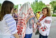 ZAPORIZHZHIA, UKRAINE - MAY 16, 2024 - A participant of the World Vyshyvanka Day celebration stands under the "Womenâs Happiness" embroidered towel on Festyvalna Square, Zaporizhzhia, southeastern Ukraine. (UKRINFORM/POLARIS