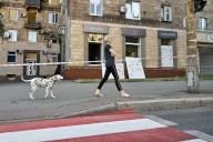 ZAPORIZHZHIA, UKRAINE - JUNE 1, 2024 - A woman walks a Dalmatian dog past a residential building after the Russian missile attack in Zaporizhzhia, southeastern Ukraine. In Zaporizhzhia, traffic is temporarily blocked across the Dnipro hydropower plantâs dam while 20 houses sustained damage as a result of Russian strikes. In the early hours of Saturday, June 1, Ukraineâs air defence forces shot down 35 cruise missiles and 46 Shahed-131/136 one-way attack drones. In total, Russian troops launched 53 missiles of various types and 47 attack UAVs. (Ukrinform/POLARIS