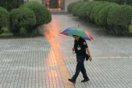 A police officer holding an umbrella walks under heavy rain inside inner yard of the Legislature Yuan building in Taipei, Taiwan, on May 21, 2024 in Taipei, Taiwan.//DATICHE_ND202405210006/Credit:Nicolas Datiche/SIPA