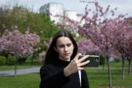 A girl takes a selfie against the backdrop of blooming sakura trees in Kyoto Park in Kyiv. (Photo by Oleksii Chumachenko \/ SOPA Images\/Sipa USA