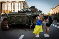 A little girl Sophia kisses her mother as she ties a Ukrainian flag to her daughter in front of the demolished Russian tank showcased in Kyiv. Amid the Independence Day of Ukraine, and nearly 6 months after the full-scale invasion of Ukraine on February 24, the country