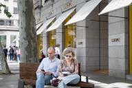 A couple sits on a bench outside the Spanish luxury clothing and accessories brand Loewe store in Spain. (Photo by Xavi Lopez / SOPA Images/Sipa USA