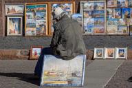 An artist sits in front of his paintings on one of the streets of St. Petersburg on a summer day. (Photo by Artem Priakhin \/ SOPA Images\/Sipa USA