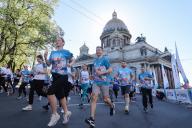 RUSSIA, ST PETERSBURG - MAY 19, 2024: Runners pass St Isaac