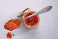 Ajvar in a jar and on a spoon (view from above)
