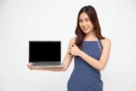 Happy Asian woman showing blank laptop computer screen over white background and Looking at camera