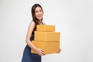 Happy Asian woman holding package parcel box isolated on white background, Delivery courier and shipment service concept