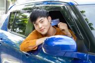 Young Asian man holding credit card and sitting in car