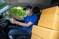 Asian Delivery man courier with face mask driving car delivering parcel boxes