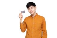 Young Asian man holding credit card isolated on white background