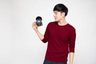 Young Asian man photographer holding camera isolated on white background