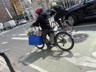 Delivery person in bike lane on E-bike with flower bouquets, Manhattan, New York