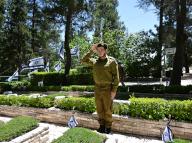 An Israeli soldier salutes after placing a national flag with a black ribbon on the grave of a soldier ahead of Memorial Day for fallen soldiers at the Mt. Herzl Military cemetery in Jerusalem, Wednesday, May 8, 2024. Israel will observe Memorial Day from sunset May 12 until sunset May 13, when Independence Day begins. Photo by Debbie Hill