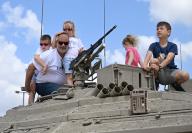 A family poses for a photo on top of a tank at the Latrun Tank Museum on Israel