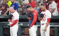 St. Louis Cardinals (L to R) coach Stubby Clapp, coach Daniel Descalso and manager Oliver Marmol bow their heads as the Cardinals recognize veterans with a moment of silence before a game against the Chicago Cubs at Busch Stadium in St. Louis on Sunday, May 26, 2024. Photo by Bill Greenblatt