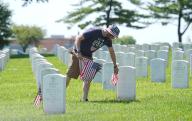 A volunteer removes American flags from the graves at Jefferson Barracks National Cemetery in St. Louis on Tuesday, May 28, 2024.Scouts placed an American flag on each of the 247,000 graves at Jefferson Barracks on May 25, 2024, with volunteer groups returning to removes them, one day after Memorial Day. Photo by Bill Greenblatt