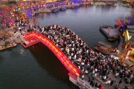 VCG111420037508 KAIFENG, CHINA - JANUARY 28: Aerial view of tourists walking at a red-colored bridgeduring a lantern show at Millennium City Park, also known as Qingming Riverside Landscape Garden, on January 28, 2023 in Kaifeng, Henan Province of China. (Photo by VCG\/VCG