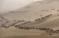 VCG111494187714 DUNHUANG, CHINA - MAY 03: Tourists riding camels visit Mingsha Mountain And Crescent Spring scenic spot during the May Day holiday on May 3, 2024 in Dunhuang, Jiuquan City, Gansu Province of China. (Photo by Zhang Xiaoliang\/VCG