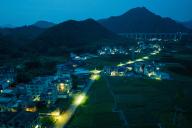 VCG111494971453 WUZHOU, CHINA - MAY 07: Aerial view of residential houses illuminated by solar-powered street lights at Beilou village on May 7, 2024 in Wuzhou, Guangxi Zhuang Autonomous Region of China. (Photo by Huang Shenglin\/VCG