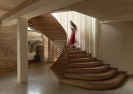 Sculptural curvaceous timber staircase with figure ascending. ACME Offices, London, United Kingdom. Architect: ACME, 2024