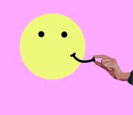 Hand placing or removing smile onÂ anthropomorphic smiley face
