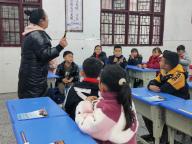 (240301) -- CHONGQING, March 1, 2024 (Xinhua) -- This photo taken with a mobile phone shows Wu Jing teaching the Miao language to third-graders at Minzu Primary School in Minzu Village, Meijiang Township, Xiushan Tujia and Miao Autonomous County in southwest China