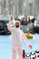 (240509) -- MARSEILLE, May 9, 2024 (Xinhua) -- French singer JuL holds the Olympic torch before lighting the Olympic cauldron during a ceremony welcoming the Olympic flame of Paris 2024 at the Vieux-Port (Old Port) in Marseille, southern France, on May 8, 2024. (Photo by Julien Mattia\/Xinhua