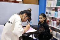 (240515) -- RABAT, May 15, 2024 (Xinhua) -- A young girl watches a student from the Confucius Institute at the Mohammed V University writing her name in Chinese calligraphy during the 29th edition of the International Book and Publishing Fair in Rabat, Morocco, May 14, 2024. Chinese calligraphy has charmed many Moroccan people in cultural events held here on Tuesday. (Xinhua/Huo Jing