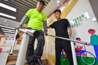 (240518) -- CHANGSHA, May 18, 2024 (Xinhua) -- Lin Mingchang (R) helps a disabled man do rehabilitation exercises at a service center for the disabled in Dayao Township of Liuyang City, central China\
