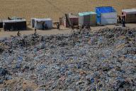 (240520) -- KHAN YOUNIS, May 20, 2024 (Xinhua) -- People walk past garbage at a temporary camp in the southern Gaza Strip city of Khan Younis, May 19, 2024. (Photo by Rizek Abdeljawad/Xinhua