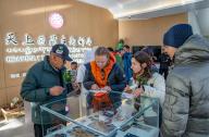 (240526) -- LHASA, May 26, 2024 (Xinhua) -- Natalia Yanina (2nd L), a tourist from Russia, and Simona Borghesio (2nd R), a tourist from Italy, stamp postcards in a post office at the Mount Qomolangma base camp for tourists in Zhaxizom Township of Tingri County in Xigaze City, southwest China