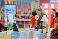 (240530) -- BUCHAREST, May 30, 2024 (Xinhua) -- A visitor holds her child while looking at books on display during the opening day of the 17th edition of Bookfest, an international book fair, in Bucharest, Romania, May 29, 2024. The five-day event attracts about 200 exhibitors. (Photo by Cristian Cristel/Xinhua